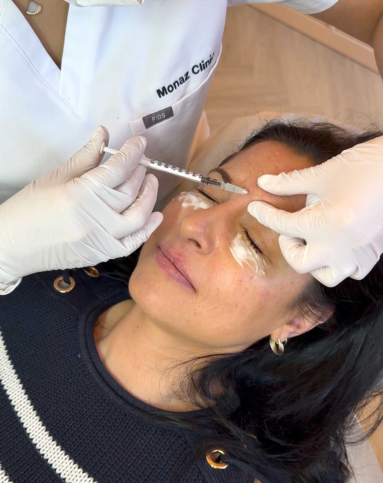 Patient receiving anti-wrinkle injection treatment to address frown and forehead lines under professional medical care.