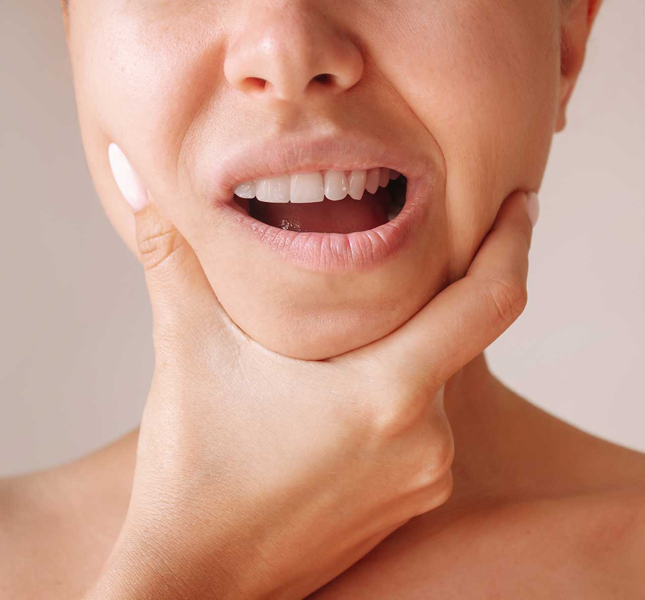 Woman holding jaw due to tension, representing patients suitable for Anti-Wrinkle Injections for Teeth Grinding and Jaw Clenching (Bruxism) at Monaz Clinic.